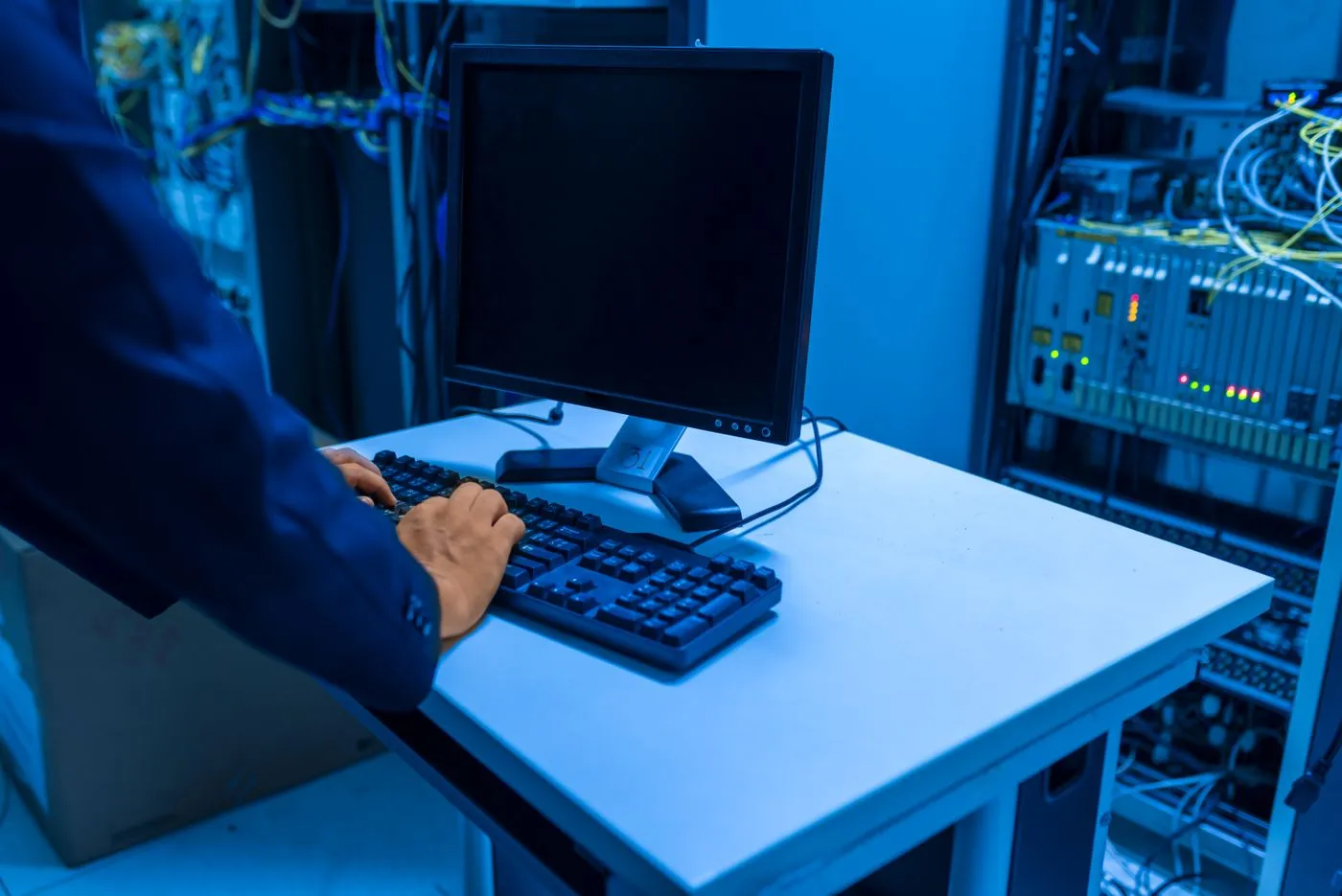 A technician typing at a terminal between server racks